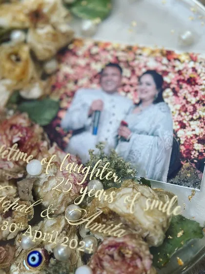 A detailed shot of an anniversary keepsake. The engraving reads "a lifetime of laughter, 25 years of smile" along with the couple's names and celebration date.