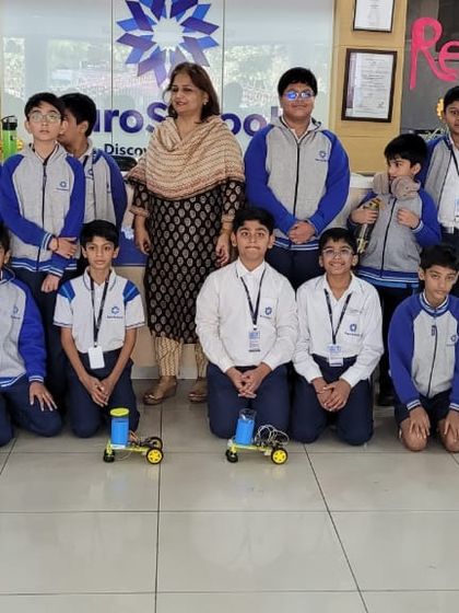 Students and a teacher from Euro International School pose with the floor-cleaning robots they built during our hands-on workshop.
