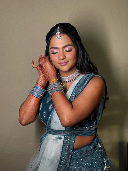 A beautiful moment of the bride adjusting her earring, the light catching the shimmer on her eyelids.