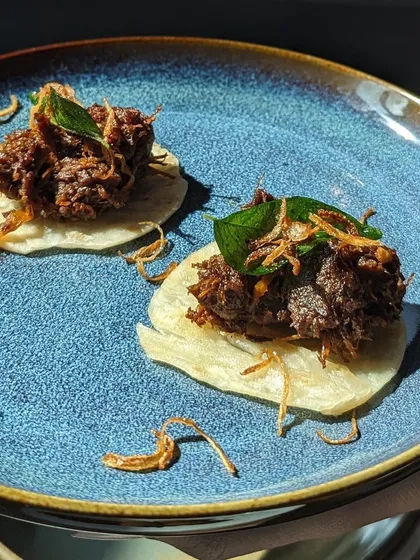 I love making traditional dishes easy to enjoy at parties. This is my Beef Ullarthu, slow roasted with coconut chips and curry leaves until it's incredibly tender, served on a bite-sized mini parotta. It’s a true taste of Kerala in one perfect bite.