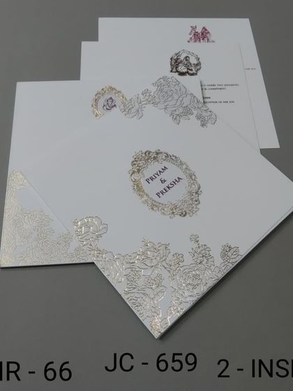 A clean white invitation featuring delicate silver foil floral embossing. The design is elegant and timeless, perfect for a classic wedding.