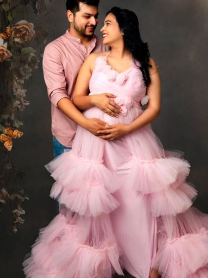 A romantic portrait of a couple surrounded by flowers, with the mom-to-be in our soft pink ruffled gown.