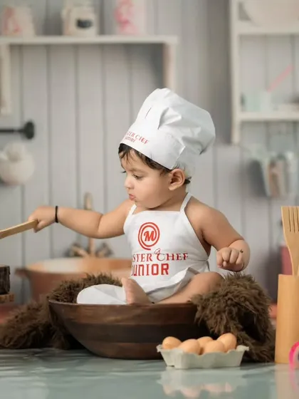 This little chef is hard at work, "cooking" with a wooden spoon. Our interactive setups allow for candid moments of play during the photoshoot.