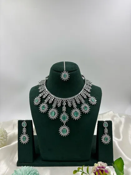 Showcasing the modern side of our collection, this silver-plated American Diamond set features a unique sunburst design. It's available in multiple stone colors including white, black, and mint green, perfect for cocktail parties and contemporary tastes.