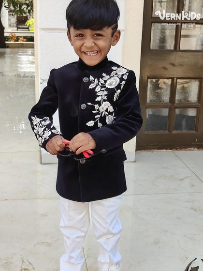 That smile, that swag, and that perfect outfit. Our little client is owning the wedding in our black velvet Indo-western jacket, ready to dance the night away.