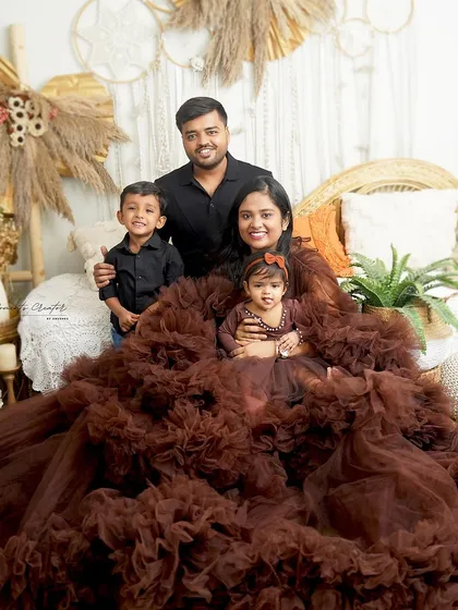A stunning family portrait where the mother's dramatic brown ruffled gown is the centerpiece. It's a high-fashion take on a family photoshoot.