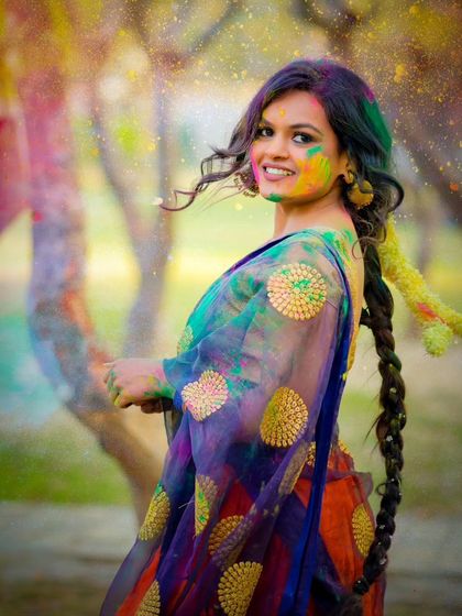 A playful and colorful portrait from a Holi-themed outdoor shoot. The movement of the saree adds a dynamic feel.