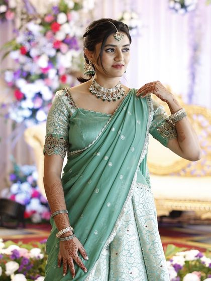 A full-length photo of Preethi's elegant event look. The soft makeup and traditional hairstyle are perfect for her pastel-colored outfit.