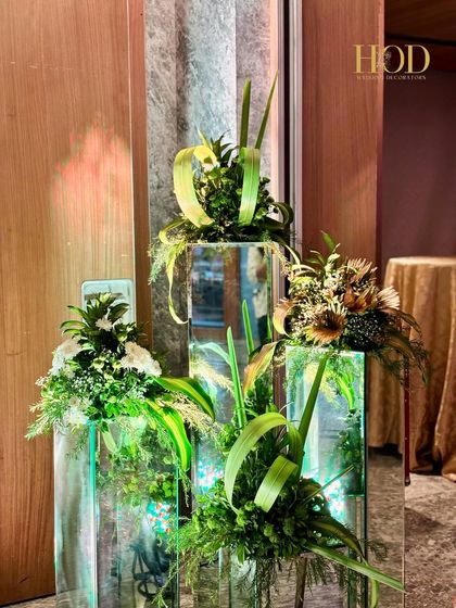 A unique floral arrangement on mirrored pedestals, adding a touch of modern elegance to a sangeet or cocktail party decor.