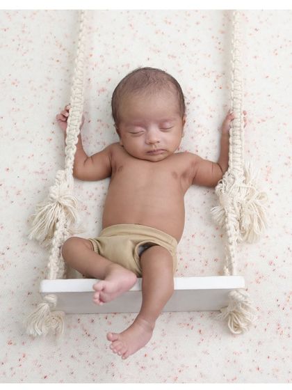 A simple and modern portrait on a miniature swing. The clean background and neutral tones make this a timeless and artistic image.