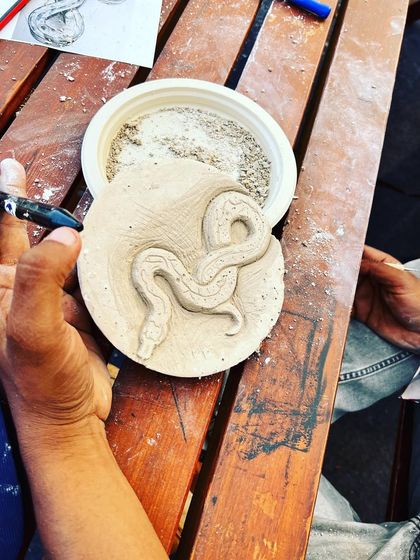 A detailed carving of a snake on a round block, created during our hands-on workshop at the Royal Enfield festival.