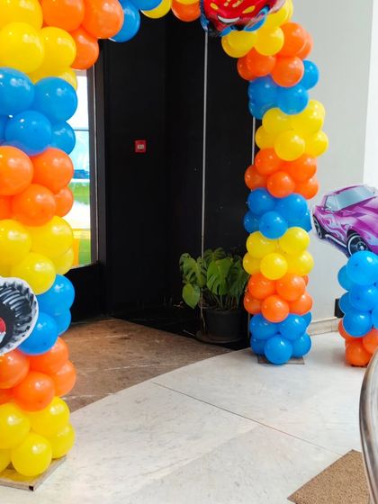 A colorful balloon arch in orange, blue, and yellow at the entrance of the Hot Wheels party.