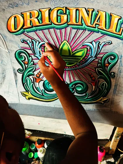 A close-up look at my hand-painting process shows the precision and care that goes into each brushstroke. Here, I am adding fine details and color gradients to the 'Original' hoodie, building up the layers to create a rich, three-dimensional effect.