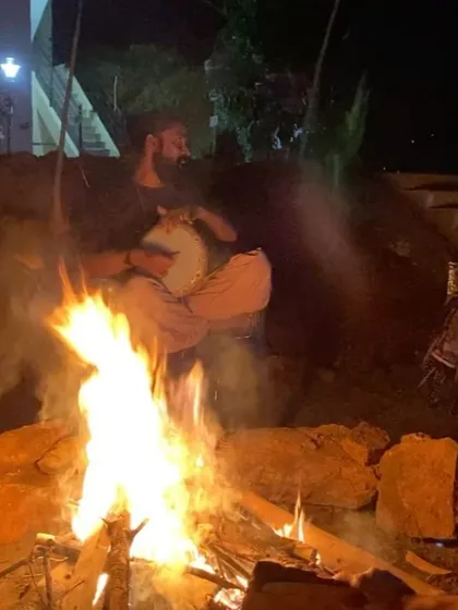 This is a duplicate of image 62, showing our community gathered around the bonfire at night, a time for connection, music, and spiritual sharing.