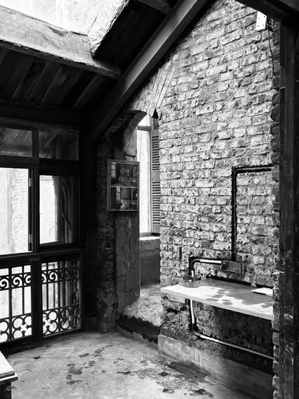 The beginning of a new journey. This black and white image captures the raw potential of a historic space, with its exposed brick and original ironwork, before our intervention begins.