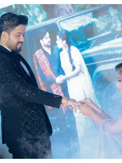 The ring exchange on stage, with a projection of their pre-wedding photo in the background. This unique setup adds a personal and modern touch to their ceremony.