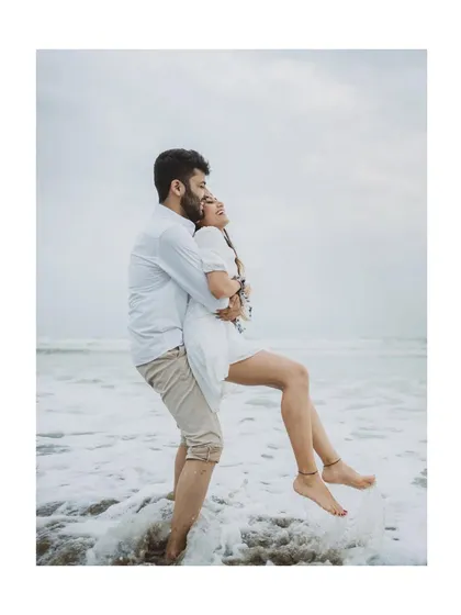 A groom lifts his fiancée in the ocean waves in Goa. We capture dynamic, fun, and romantic moments for adventurous couples.