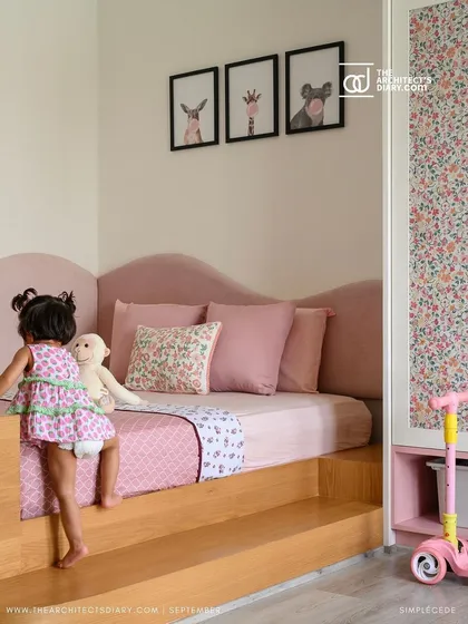 This toddler's room features a custom platform bed with a soft, curved pink headboard, designed to be both safe and playful.