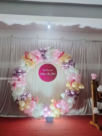 A naming ceremony setup with a circular balloon backdrop and a traditional wooden cradle.