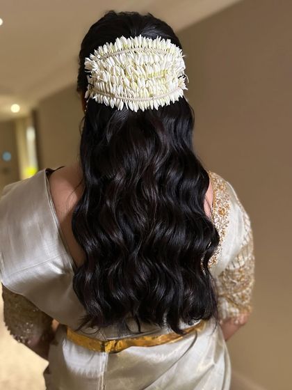 A classic South Indian inspired half-updo. I styled the hair in soft waves and added a traditional 'gajra' of Malligi (jasmine) blooms for an elegant and fragrant touch.