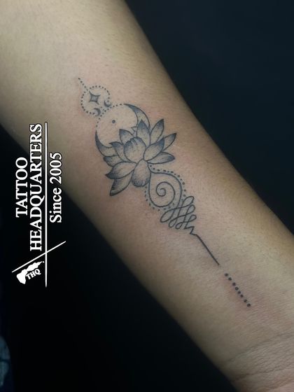 A delicate Unalome tattoo combined with a lotus and crescent moon. This fine-line piece symbolizes spiritual growth and the path to enlightenment.