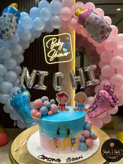A duplicate image of the gender reveal setup, providing a clear, static view of the cake, neon sign, and balloon ring.