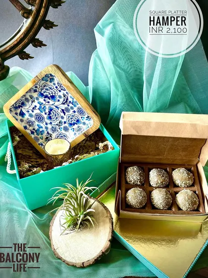 I love how this hamper turned out. The star is the beautiful square platter with its intricate blue and white enamel work, paired with a box of delicious upcycled sweets. We added a little botanical friend, an air plant, nestled in a rustic wood holder to bring a touch of green life to your home.