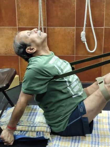 A demonstration of Navasana (Boat Pose) using a chair and strap for support. This variation, taught in an online workshop, helps build core strength.