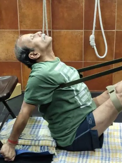 A demonstration of Navasana (Boat Pose) using a chair and strap for support. This variation, taught in an online workshop, helps build core strength.