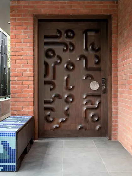 The main door of 'The Nest' in Ahmedabad is a piece of art in itself, with a custom-carved abstract pattern that creates a playful and unique entrance.