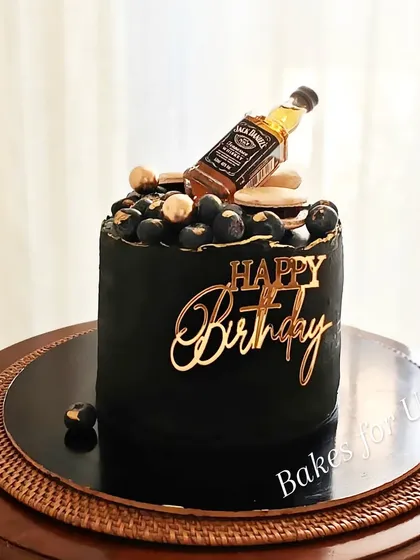 A Jack Daniel's-themed cake for a whiskey lover. This black cake is flavored with Ferrero Rocher and topped with fresh blueberries and a miniature bottle of Jack Daniel's.