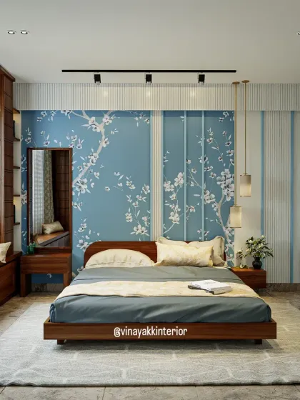 This bedroom design uses a serene blue and wood theme. The floral wallpaper behind the bed acts as a beautiful accent, complemented by the clean lines of the wooden bed frame and the custom white and gold wardrobe, creating a fresh and modern look.