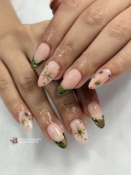 A celestial-inspired look with a soft nude base, golden star decals, and textured gold tips. This almond-shaped manicure is perfect for a touch of dreamy glam.