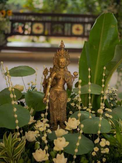 A brass deity nestled among fresh lotus pads and white blooms. I believe in styling spaces that feel soulful, using elements that are both beautiful and spiritually significant to the couple.