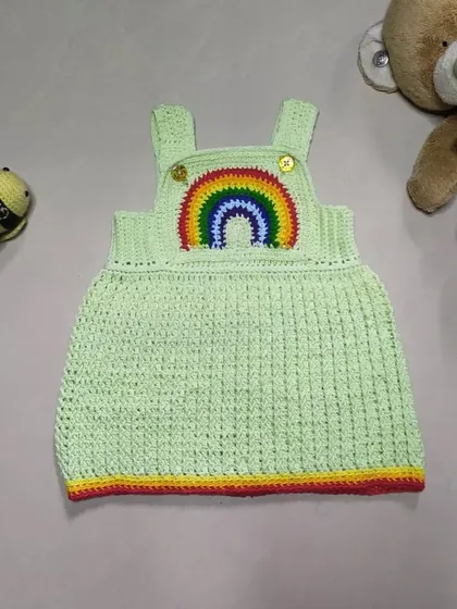 The Lucky Rainbow Dress is such a happy piece. Made with a soft green cotton yarn and a vibrant rainbow applique, this overall-style dress is both comfortable for playtime and cute enough for any special day.