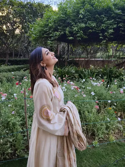 A candid shot of a model enjoying a garden, wearing the peach-brown tasselled hoop earrings.