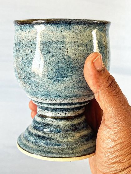 Holding the blue ceramic goblet to show its scale. It feels substantial and balanced in the hand.