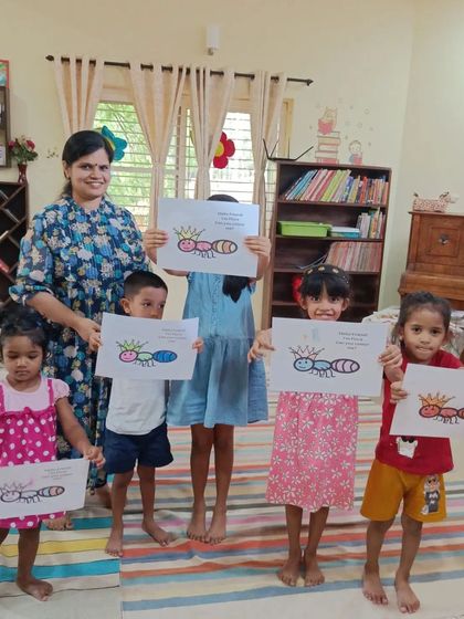 The storyteller and children proudly present their colorful ant drawings. Each piece of art is unique and celebrated.