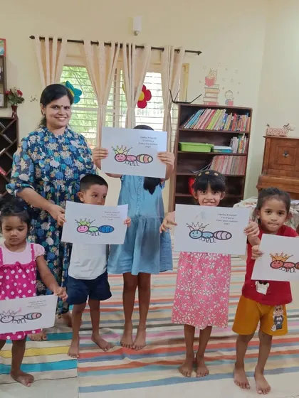 The children proudly present their ant queen drawings. This craft activity followed a story about good manners and keeping promises, with each child coloring their own royal ant.