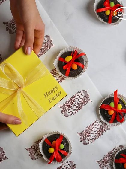 Gifting our Easter treats. This image shows our chocolate nests being packed into a bright yellow gift box, tied with a ribbon.