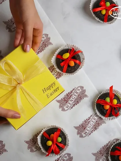 For Easter, we create these cheerful yellow gift boxes. Here you can see one being prepared, surrounded by our special Easter nest chocolates topped with candy eggs.