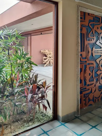 Looking from the inside out, the door's intricate metalwork creates a dynamic play of shape and color against the natural backdrop, connecting the interior space with the garden beyond.
