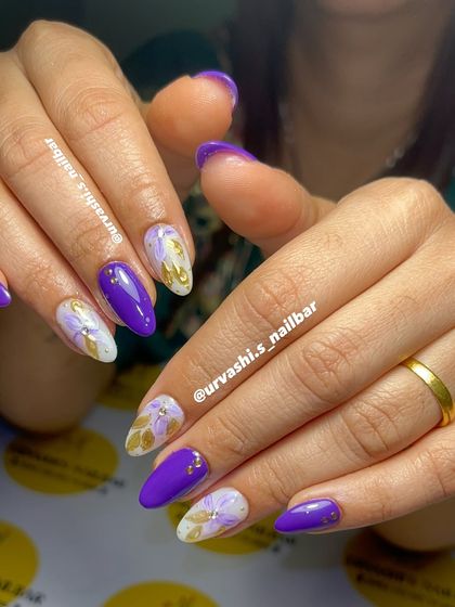 I love this bold combination of vibrant purple and hand-painted golden florals. The contrast is stunning, and the tiny gold studs add just the right amount of detail to this artistic manicure.