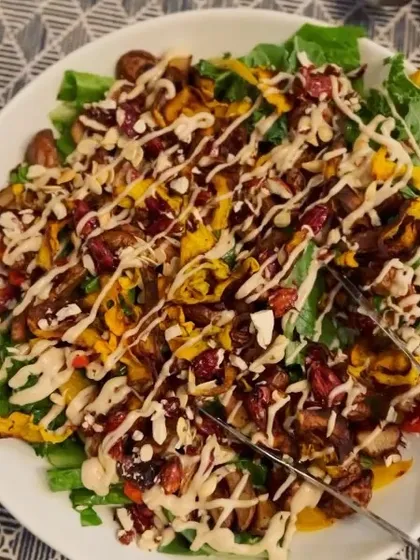 A beautiful, hearty salad drizzled with a creamy, oil-free dressing. This dish is full of texture and flavor, with fresh greens, roasted vegetables, and crunchy toppings, showing that salads can be a satisfying meal.