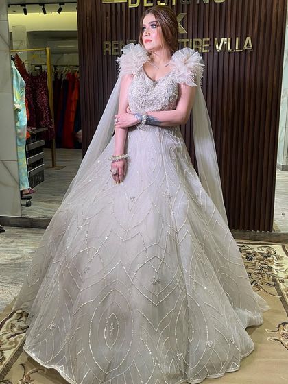 A full-length shot of the beige ball gown with its feathered cape. This is a high-end designer piece available for rent, allowing you to enjoy luxury for your special day.