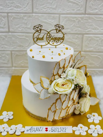 Simple elegance for a special announcement. This two-tiered "Just Engaged" cake features a clean white finish, delicate sugar flowers, and gold accents for a timeless look.