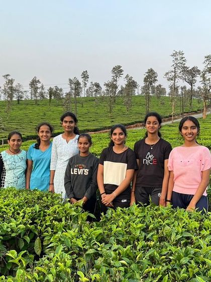 A group of girls poses for a photo in the tea gardens, capturing a beautiful memory from their camp experience.