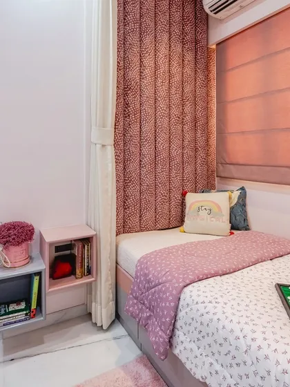This cozy bedroom corner is designed with a soft pink and grey palette. The plush, channel-tufted headboard adds a touch of luxury and comfort, while the floating bedside shelf provides a convenient spot for books and essentials.
