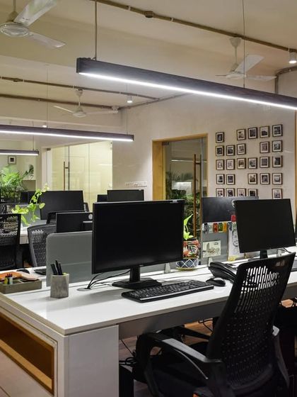 The main workspace at the SAS office. I designed it to be open, minimal, and collaborative, with clean white desks, ergonomic chairs, and linear pendant lighting. A gallery wall of project photos adds a personal and inspiring touch.