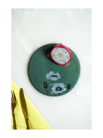 A minimalist shot of a hand-painted plate with a dragon fruit slice, highlighting the plate's design.